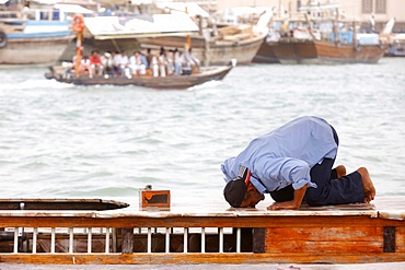 Praying muslim in Dubai harbour, Dubai, United Arab Emirates, Middle East