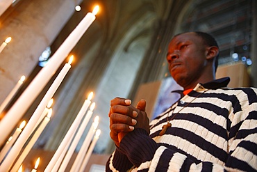 Man praying with candles in church, Amiens, Somme, France, Europe