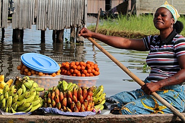 African woman mark paddling a canoe carrying fruit to market, Ganvie, Benin, West Africa, Africa