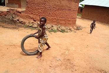 African girl having fun rolling an old tyre, Tori, Benin, West Africa, Africa