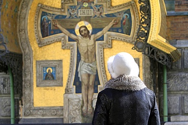 Russian woman praying in front of Christ, Church of Our Saviour on Spilled Blood (Church of Resurrection), St. Petersburg, Russia, Europe.