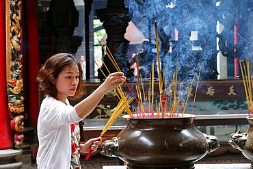 Buddhist worshipper placing incense sticks on joss stick pot, Taoist temple, Phuoc An Hoi Quan Pagoda, Ho Chi Minh City, Vietnam, Indochina, Southeast Asia, Asia