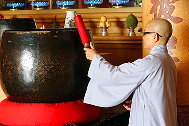 Vietnamese Buddhist nun using a giant singing bowl, Vung Tau, Vietnam, Indochina, Southeast Asia, Asia