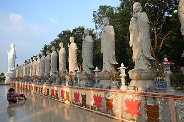 Woman praying in front of Buddha Amitabha statues, Dai Tong Lam Tu Buddhist Temple, Ba Ria, Vietnam, Indochina, Southeast Asia, Asia