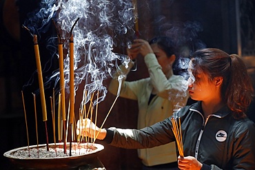 Taoist temple, Emperor Jade pagoda (Chua Phuoc Hai), Buddhist worshipper burning incense sticks, Ho Chi Minh city, Vietnam, Indochina, Southeast Asia, Asia