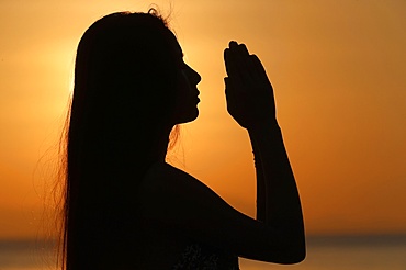 Silhouette of a woman standing by the sea at sunset doing yoga pose and meditation, Kep, Cambodia, Indochina, Southeast Asia, Asia