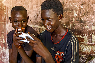 Apprentices using a cell phone in a garage in Fatick, Senegal, West Africa, Africa