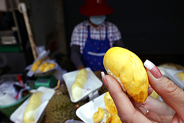 A woman prepares Durian fruit for sale at a street food stall popular with tourists and locals, Bangkok, Thailand, Southeast Asia, Asia