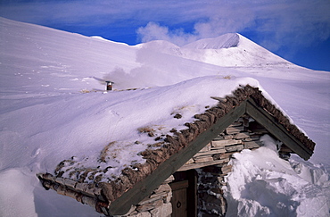 Smoke from chimney as stove is fired up inside a buried stone hut, Rondane National Park, Norway, Scandinavia, Europe