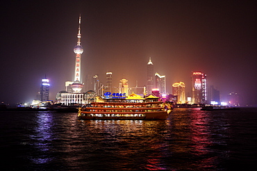 Boat set against Shanghai illuminated skyline, Shanghai, China, Asia