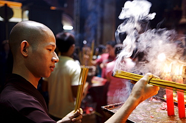 Monk lighting joss sticks during ceremony in a Buddhist temple, Ho Chi Min City, Vietnam, Indochina, Southeast Asia, Asia