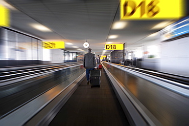 Businessman with luggage on travelator at Schiphol airport, Amsterdam, Netherlands, Europe