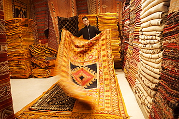 Carpet shop interior with shop keeper showing rug, Marrakesh, Morocco, North Africa, Africa