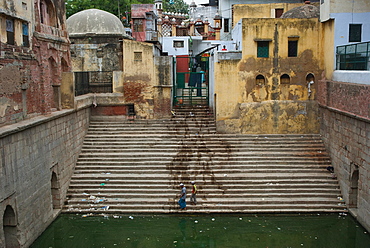 Water spilled on stairs and buildings with two men at the bottom of the stairs, Delhi, India, Asia