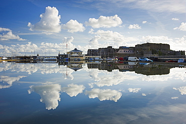 Guernsey Yacht Club and Castle Cornet reflected in the still water of a model boat pond at St. Peter Port, Guernsey, Channel Islands, United Kingdom, Europe