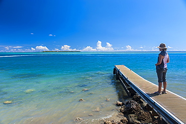 Tourist standing on a little pier with Cocos Island in the distance, Guam, US Territory, Central Pacific, Pacific