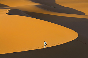 Tourist walking along a giant sand dune, Merzouga, Morocco, North Africa, Africa