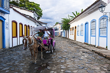 Horse cart with tourists riding through the town of Paraty, Rio de Janeiro, Brazil, South America