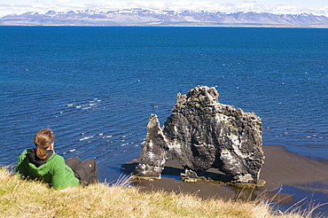 Tourist relaxing at the famous Hvitserkur rock formation, Vatnsnes Peninsula, Iceland, Polar Regions