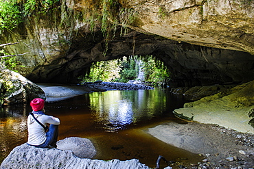 Woman enjoying the stunning Moria Gate Arch in the Oparara Basin, Karamea, West Coast, South Island, New Zealand, Pacific