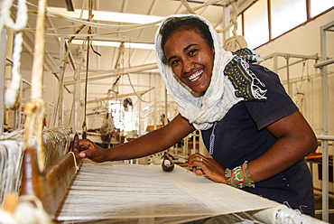 Friendly woman working on a hand weaving loom on a social project in the highlands of Eritrea, Africa