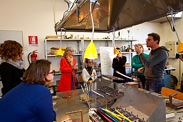 Muranese instructor teaching to a group of students the lampworking technique to make glass beads, Abate Zanetti glass school, Murano island, Venice, Veneto, Italy, Europe