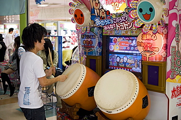 Boy playing a Japanese taiko drum video game at a game center, Japan, Asia