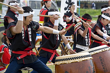 Energetic group of drummers beating Japanese taiko drums during an outdoor performance, Japan, Asia