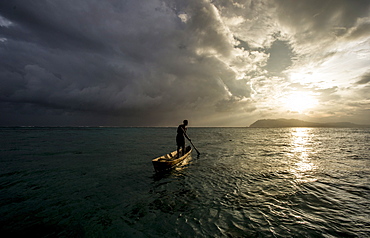 A man in a dug out canoe at sunset, Solomon Islands, Pacific 