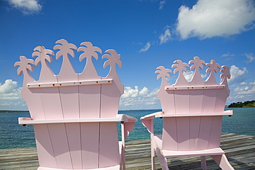 Wooden pink beach chairs with backs carved in the shape of palm trees