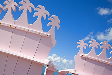 Detail of wooden pink beach chairs with backs carved in the shape of palm trees