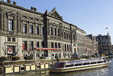 A sightseeing boat by the Allard Pierson Museum on the Rokin canal in central Amsterdam, Netherlands, Europe