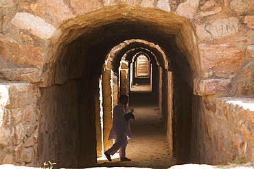 An Indian man visits the dungeons of Tughluqabad Fortress, constructed under Ghiyas-ud-Din in 1321 AD and abandoned in 1327 AD, Delhi, India, Asia