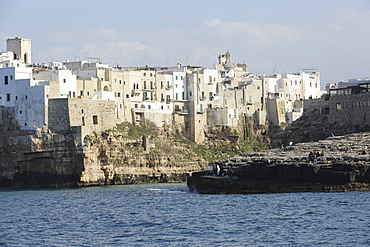 Clifftop houses, built onto rocks, surround the natural cove forming the harbour of Polignano a Mare, Apulia, Italy, Europe