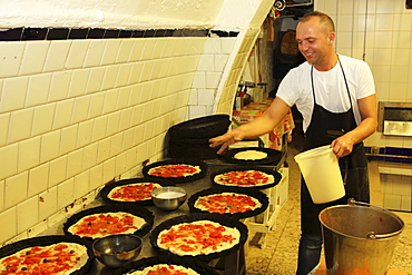 A baker at work making focaccia, a local delicacy, in a bakery in the Bari Vecchia quarter of Bari, Apulia, Italy, Europe