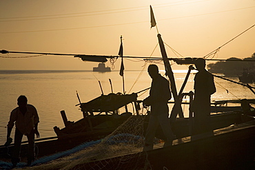 Fishermen, silhouetted in the golden light of dawn at Diu, Union Territory of Diu and Daman, India, Asia