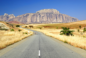 Malagasy couple walking on the road leading to Fandana, the gateway to the south, a rock formation alongside the RN7 road in southwest Madagascar, Madagascar, Africa