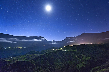 Night view of stars and the moon above the Cirque de Cilaos caldera on the French island of Reunion in the Indian Ocean, Africa