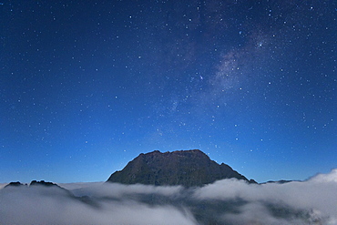 Night-time view of a mountain peak poking above the clouds on the French island of Reunion in the Indian Ocean, Africa