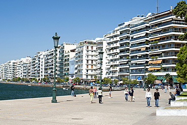 View of buildings on Nikis Avenue and pedestrians strolling on the waterfront in Thessaloniki, Greece, Europe