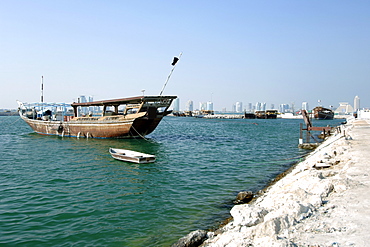 A dhow in Doha harbour with the west bay buildings in the background in Qatar.