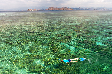 A tourist snorkeling in the waters off the western coast of Flores island, Indonesia.