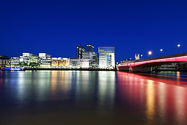 London Bridge, buildings on the south bank and the Thames river at night.