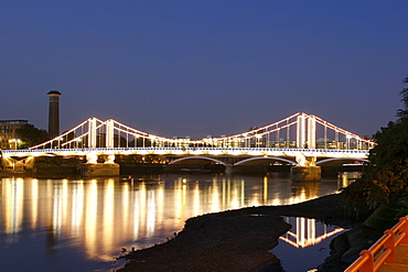 Dusk view of Chelsea Bridge and its lights reflecting in the Thames River in London.