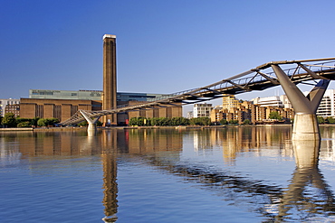 Early morning view of the Tate Modern art Gallery and Millenium Bridge reflecting in the Thames River in London. The Tate Modern is the converted former Bankside power station on the south bank of the Thames River. It was built in two phases between 1947 and 1963 and was designed by Sir Giles Gilbert Scott.