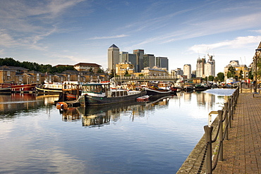 View of Canary Wharf buildings and boats moored in Greenland dock in Rotherhithe in London.