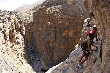 Hikers doing the Via Ferrata hike in Snake Canyon in Jebel Akhdar of the western Hajar mountains in Oman.