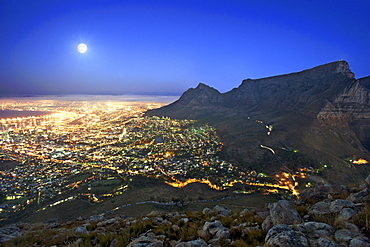 View of the full moon rising over the city of Cape Town with Table Mountain on the right.