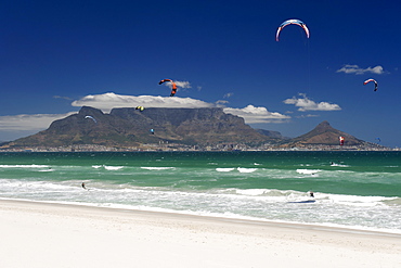 Kite surfers at Blouberg Beach with a view of Table Mountain and the city of Cape Town visible across Table Bay.