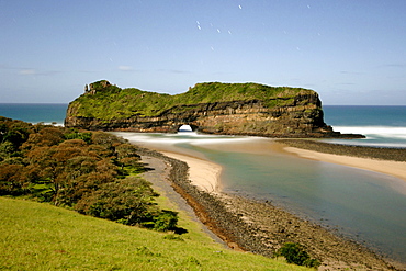 Night-time, moonlit view of the geological formation known as 'Hole in the Wall along the wild coast in a region of South Africa's Eastern Cape Province formerly known as the Transkei. Stars can be seen in the sky.